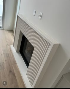 an empty room with a fire place in the center and wood floors on both sides