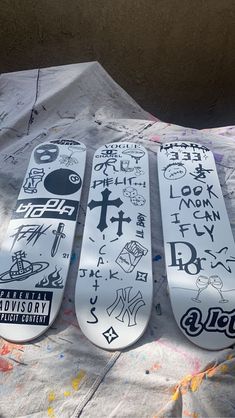 three snowboards with stickers on them sitting on a sheet of paper covered in graffiti