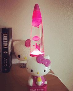 a hello kitty lamp sitting on top of a desk next to a teddy bear and books