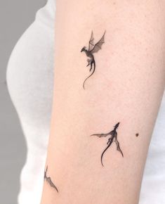 a woman's arm with two small dragon tattoos on the left side of her arm