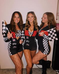 three beautiful women dressed in costumes posing for the camera with checkered flags and stockings