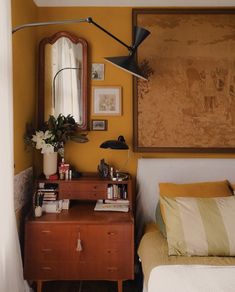 a bedroom with a bed, mirror and lamp on the wall next to a dresser