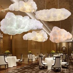 the dining room is decorated with white clouds hanging from the ceiling