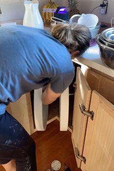 a man bending over to look at something in the kitchen