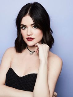 a woman with dark hair wearing a black strapless dress and red lipstick, posing for the camera