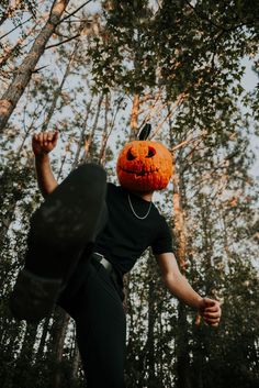 a man wearing a jack o lantern mask in the woods