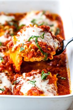 a spoon full of lasagna sauce being lifted from a casserole dish