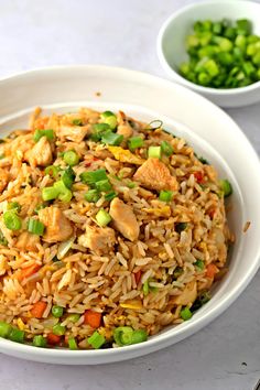 a white bowl filled with rice and veggies next to a small bowl of peas