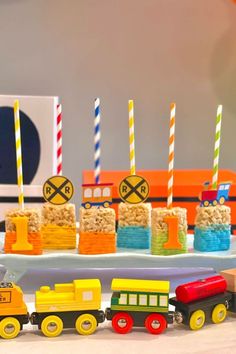 there is a train cake with candles on it and some rice krispy treats in the shape of trains