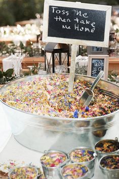 a large metal bowl filled with lots of confetti next to small bowls of food