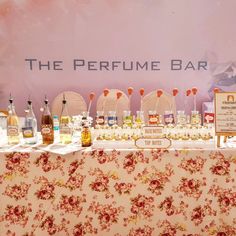 a table topped with lots of bottles and glasses next to a sign that says the perfume bar