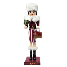 a wooden nutcracker holding a purse and wearing a red striped dress with white fur