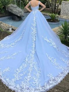 a woman wearing a blue wedding dress with white appliques on the skirt and back