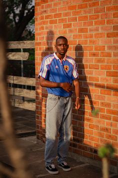 a man standing in front of a brick wall