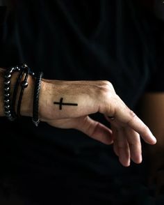 a man with a cross tattoo on his hand and bracelets around his wrist,