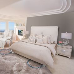 a large white bed sitting inside of a bedroom next to a chair and table on top of a rug