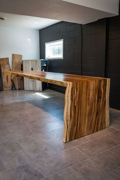 a large wooden table sitting in the middle of a room with tile flooring and black walls