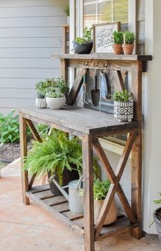 a wooden shelf with potted plants on top of it next to a white house