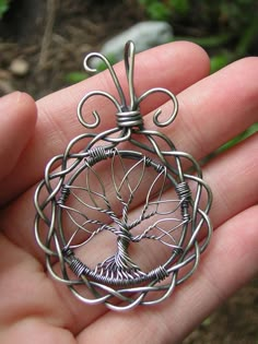 a hand holding a wire tree of life pendant in it's left palm area