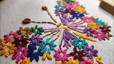 a close up of a cross stitch on a piece of cloth with flowers in it