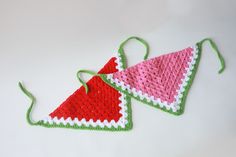 two crocheted christmas ornaments hanging on a white table with red and green trim