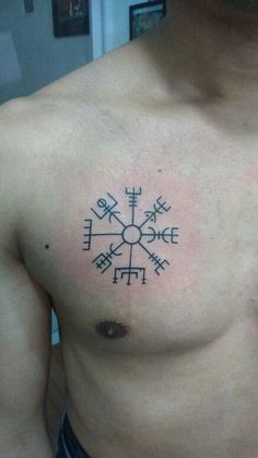 a man with a tattoo on his chest that has an image of a compass in it