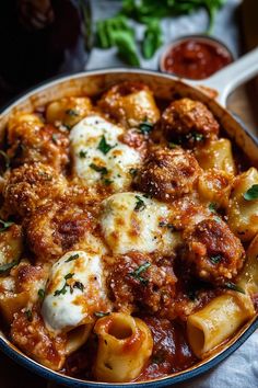 a pan filled with pasta and meatballs covered in sauce, cheese and parmesan