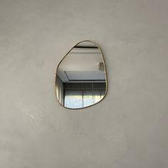 an oval mirror hanging on the wall above a sink in a room with grey walls