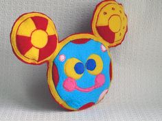 a close up of a mickey mouse head on a white surface with a red and yellow object in the background