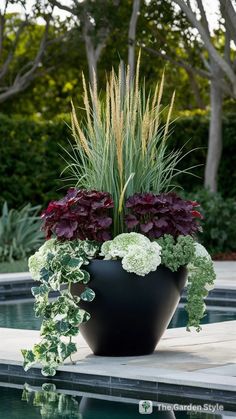 a large potted plant sitting on top of a pool next to some grass and flowers