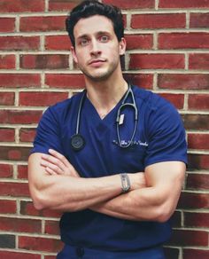 a man with a stethoscope on standing in front of a brick wall