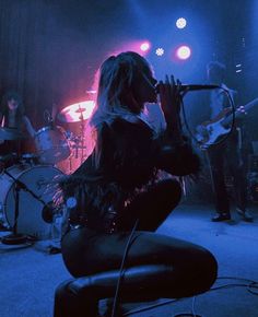 a woman sitting on top of a chair while holding a microphone in front of her