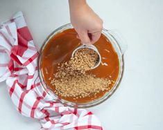 someone is adding peanut butter to the mixture in a glass bowl on a red and white checkered napkin