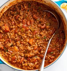 a pot filled with chili and beans next to tortilla chips on the side