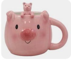 a pink ceramic pig mug with a cat on top