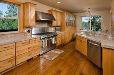 a large kitchen with wooden cabinets and stainless steel appliances in the middle of an open floor plan