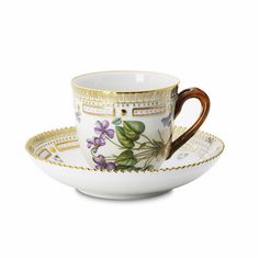 a coffee cup and saucer with gold trimmings on the rim, decorated with flowers