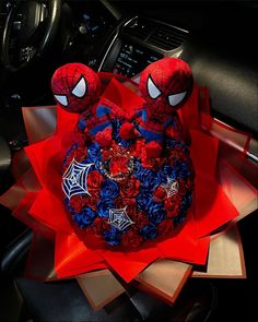 a spiderman cake with red roses and blue flowers in the shape of two heads