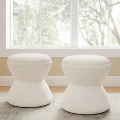 two white stools sitting on top of a carpeted floor next to a window