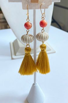 Fall in love with these pumpkin earrings with golden silky tassels, cream with gold accent miniature pumpkins and orange apple coral beads. Gold-plated, nickel-free ear wires. 3.5" drop. Adjustable Orange Tassel Earrings, Orange Tassel Earrings, Orange Tassel Dangle Earrings, Orange Beaded Tassel Earrings As Gift, Orange Tassel Drop Earrings With Dangling Beads, Elegant Orange Tassel Earrings For Gift, Orange Tassel Earrings Gift, Orange Apple, Pumpkin Earrings