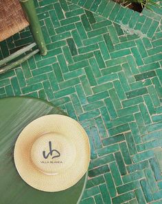 a straw hat sitting on top of a green table next to a potted plant