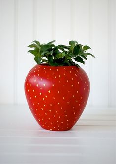 three different vases with flowers in them and one has a strawberry on the top