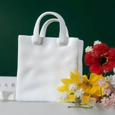 a white bag sitting next to a bouquet of flowers