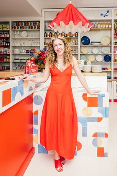 a woman in an orange dress standing behind a counter