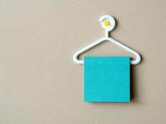 a blue piece of paper hanging from a white hanger with a button on it