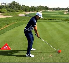 a man hitting an orange golf ball on the green with his putter's club