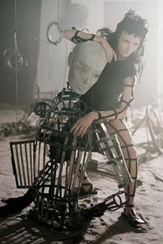 a woman is sitting on top of a chair made out of metal wires and wire