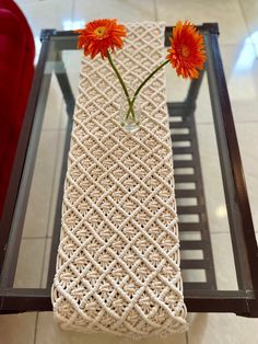 two orange flowers are placed in a vase on a table with rope wrapped around it