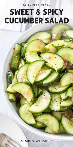 a white bowl filled with cucumber salad on top of a table next to a fork