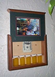 there is a framed photo hanging on the wall above an empty beer bottle holder with money in it